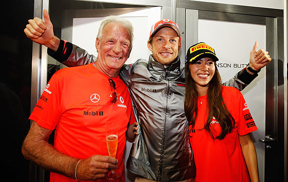Jenson Button celebrates his victory with father John and girlfriend Jessica Michibata