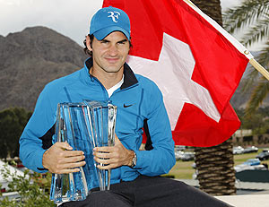 Roger Federer of Switzerland poses with his trophy and the Swiss flag after defeating John Isner of the US to win the the men's final at the Indian Wells tennis tournament on Sunday