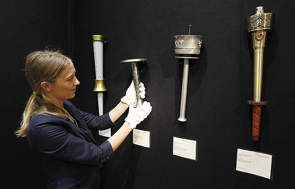 A Christie's employee poses for a photograph with a selection of Olympic torches at the art gallery in London. The torches, which are from the 1980 Moscow Olympics (left), the 1936 Berlin Olympics (2nd from left), the 1948 London Olympics (2nd right) and the 1988 Seoul Olympics were auctioned last month