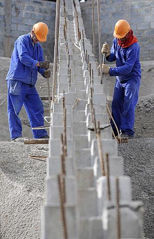 Workers lower a seat support in place at the construction site of the Corinthians Stadium in the Sao Paulo neighborhood of Itaquera