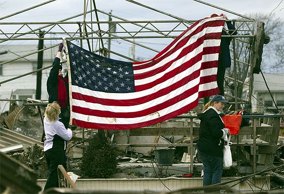 People raise the American flag among the wreckage of their homes