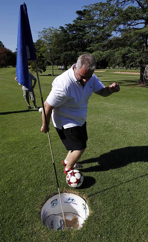 A man kicks a ball into the hole as he competes in a FootGolf tournament