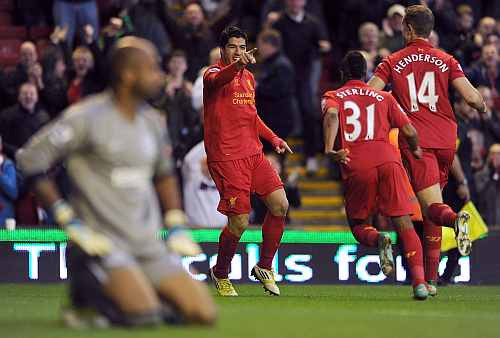 Luis Suarez of Liverpool celebrates scoring with team-mates Raheem Sterling and Jordan Henderson as Ali Al Habsi of Wigan Athletic looks dejected during the Barclays Premier League match