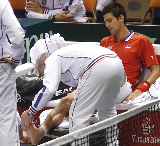 Serbia's Novak Djokovic watches his injured right ankle