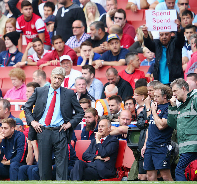 Arsenal manager Arsene Wenger looks on as a fan behind makes his feelings known during the Premier League match between Arsenal and Aston Villa at Emirates Stadium on Saturday