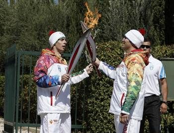 First torchbearer Yiannis Antoniou relays the flame to second torchbearer Alexander Ovechkin of Russia outside the Pierre de Coubertin monument during the torch relay September 29, 2013 in Olympia, Greece