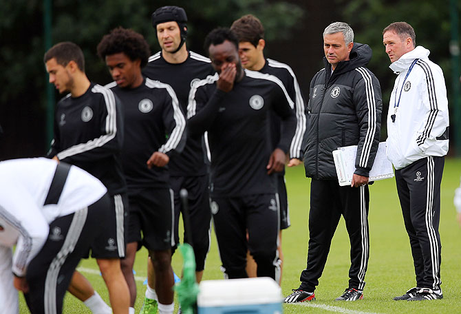 Jose Mourinho and his support team watch as Chelsea players prepare for a training session