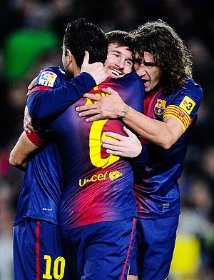 Barcelona'S Lionel Messi (centre) celebrates with teammates Xavi Hernandez (left) and Carles Puyol after scoring the opening goal against Osasuna during their La Liga match on January Sunday