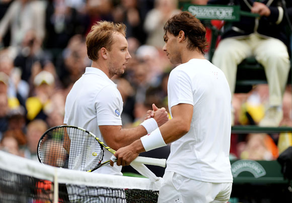 Steve Darcis of Belgium shakes hands at the net with Rafael Nadal of Spain after their first round match
