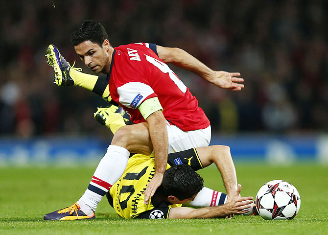 Arsenal's Mikel Arteta (top) is challenged by Borussia Dortmund's Henrikh Mkhitaryan during their Champions League match at the Emirates stadium in London on Tuesday