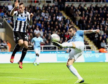 Alvaro Negredo (right) of Manchester City takes a shot as Mathieu Debuchy of Newcastle United takes evasive action during their League Cup Fourth Round match at St James' Park in Newcastle, England on Wednesday