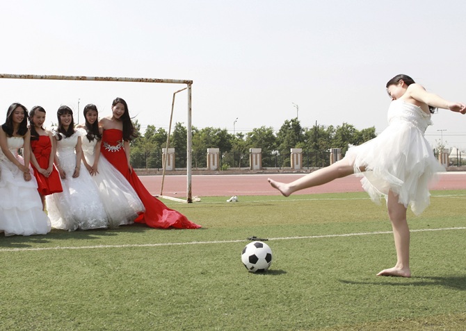 College graduates pose for a photograph with a soccer ball and a goal post on a soccer   field at Yuncheng University in Yuncheng, China