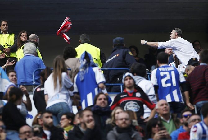 An Atletico Madrid fan, right, throws his team's scarf to Deportivo Coruna supporters during their Spanish first division soccer match