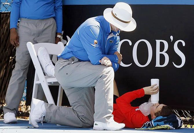 An official attends to a ball boy who collapsed during the men's singles match between Daniel Gimeno-Traver of Spain and Milos Raonic of Canada