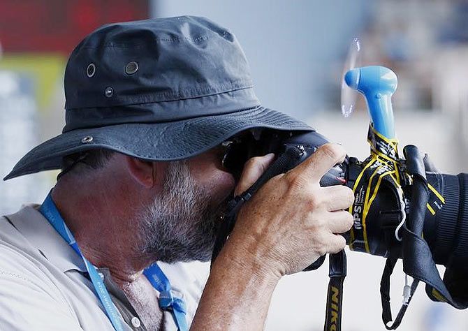 A photographer keeps cool with a fan taped to his lens as he covers the Australian Open at the Australian Open 2014 tennis tournament in Melbourne