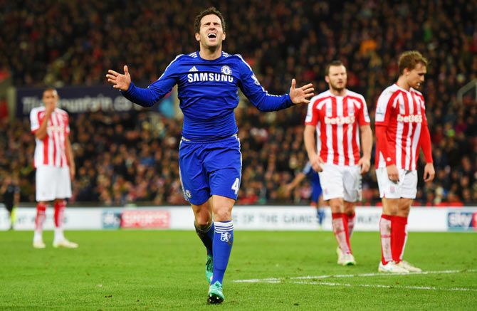 Stoke City players look dejected as Cesc Fabregas of Chelsea celebrates as he scores their second goal
