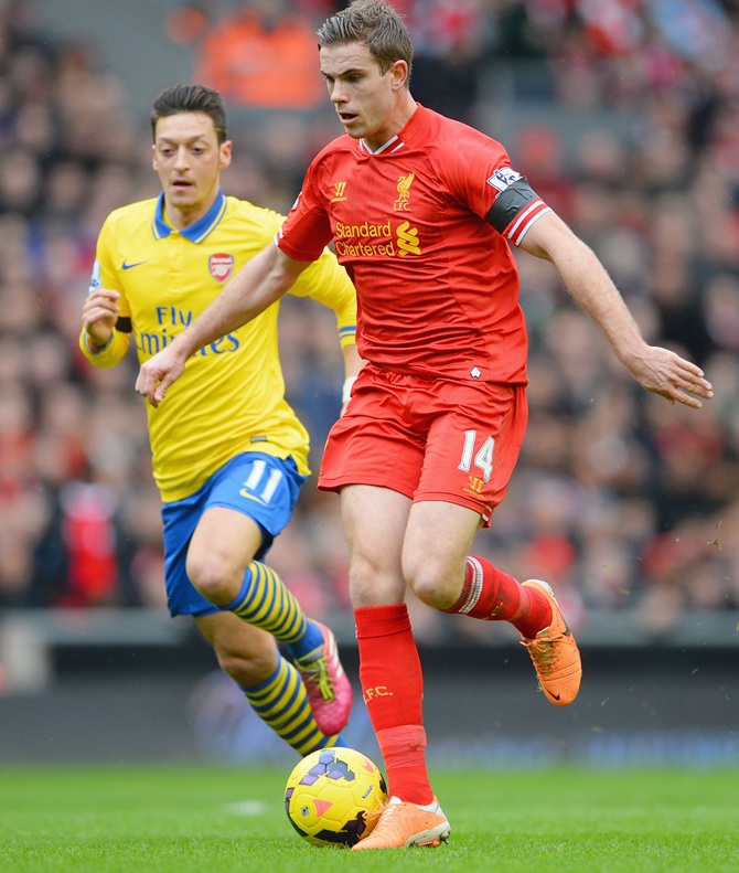 Jordan Henderson of Liverpool competes with Mesut Ozil of Arsenal.