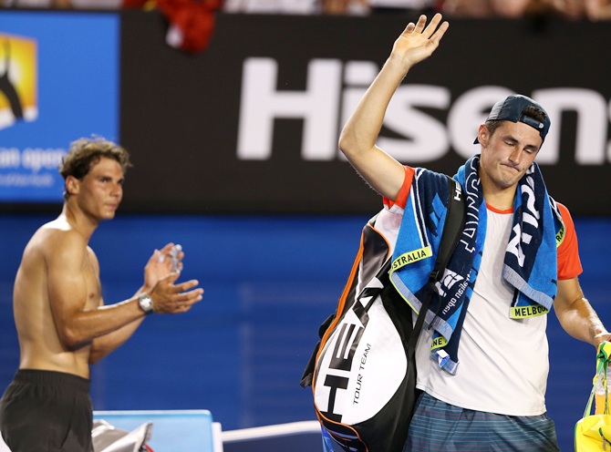 Bernard Tomic leaves the court as Rafael Nadal claps,after Tomic retired from their first round match