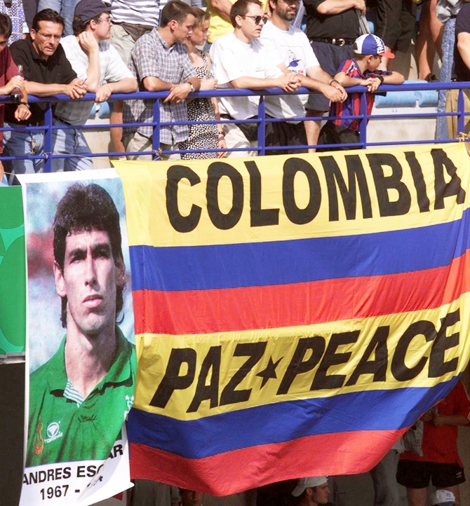 Colombian supporters watch the first round World Cup match between Colombia   and Tunisia over a Colombian flag with the inscription: 'Colombia-Peace,' placed next to a portrait of player Andres Escobar in Montpellier