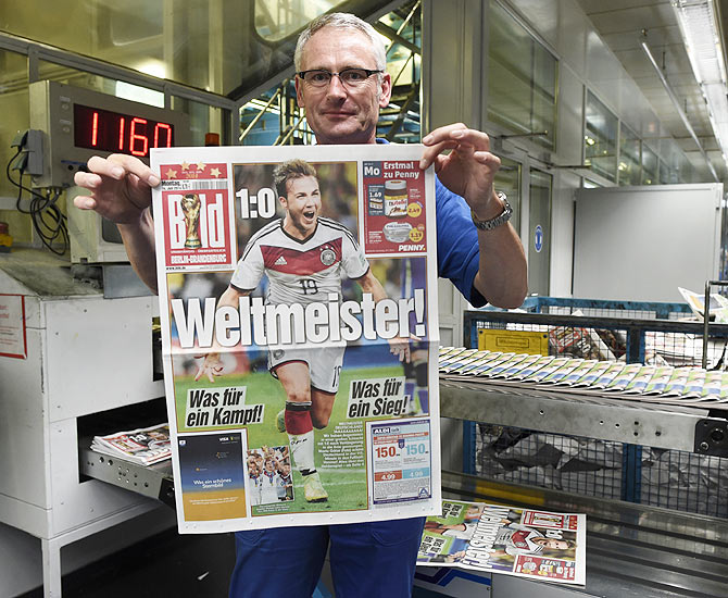 Printer Andreas Schenk shows the front page of German newspaper Bild after Germany won the 2014 Brazil World Cup final soccer match against Argentina, at the Axel Springer printing plant in Berlin on Monday