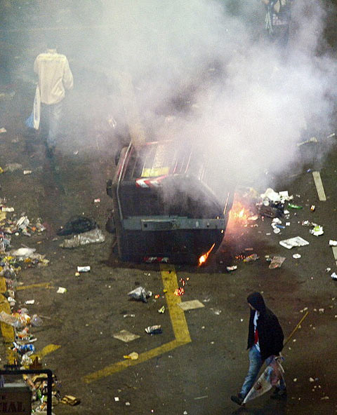 Argentine fans walk past a garbage container in flames during clashes with the police at the Obelisk in Buenos Aires following the World Cup final on Sunday