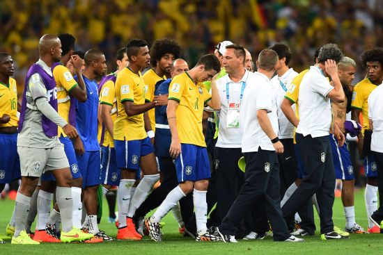 Oscar of Brazil (center) reacts with teammates after being defeated 7-1 by Germany