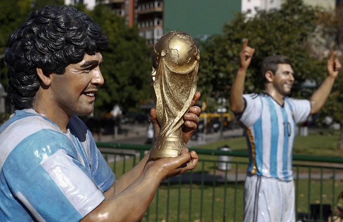 Statues of Argentine soccer star Diego Maradona, holding the FIFA World Cup trophy, and his compatriot Lionel Messi after they were unveiled, along with a statue of former Argentine striker Gabriel Batistuta, ahead of the 2014 World Cup at a public square in Buenos Aires.