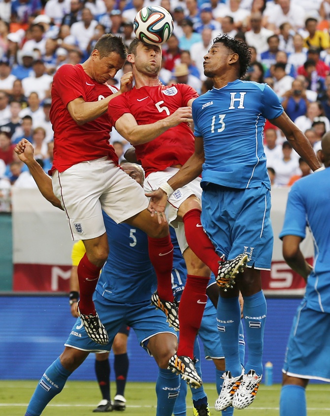 England's Gary Cahill,centre, heads the ball with help from teammate Phil Jagielka away from Honduras' Carlo Costly