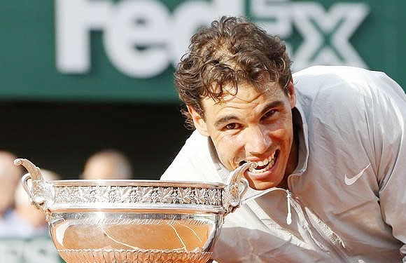 Rafael Nadal of Spain bites the trophy as he poses during the ceremony after defeating Novak Djokovic of Serbia to win the French Open title at the Roland Garros in Paris on Sunday