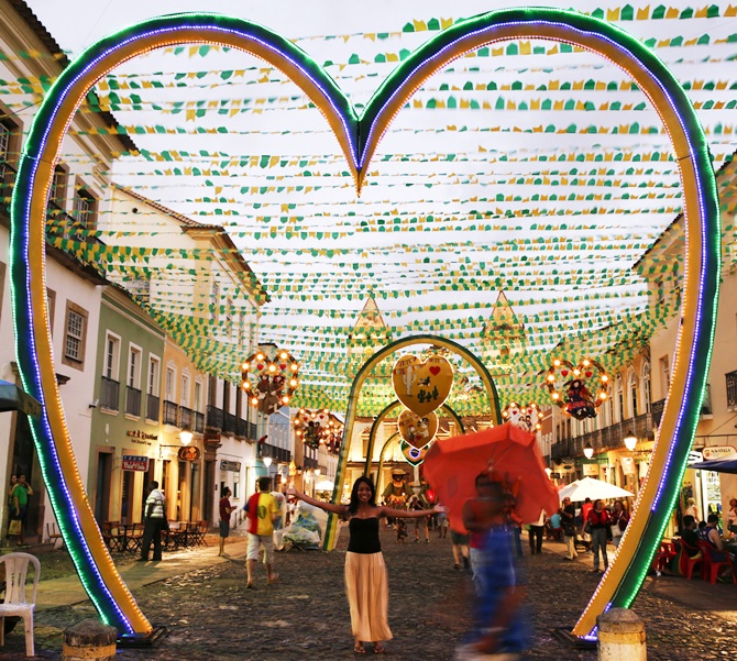 A woman pose for a picture under street decorations on the public square where the fan zone for soccer matches