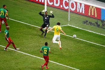 Brazil's Fred scores his team's third goal with a header past Charles Itandje of Cameroon