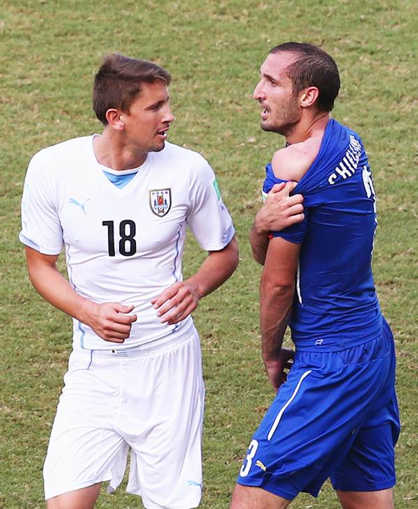 Giorgio Chiellini of Italy pulls down his shirt after being bitten by Luis Suarez (not pictured) as Gaston Ramirez of Uruguay looks on