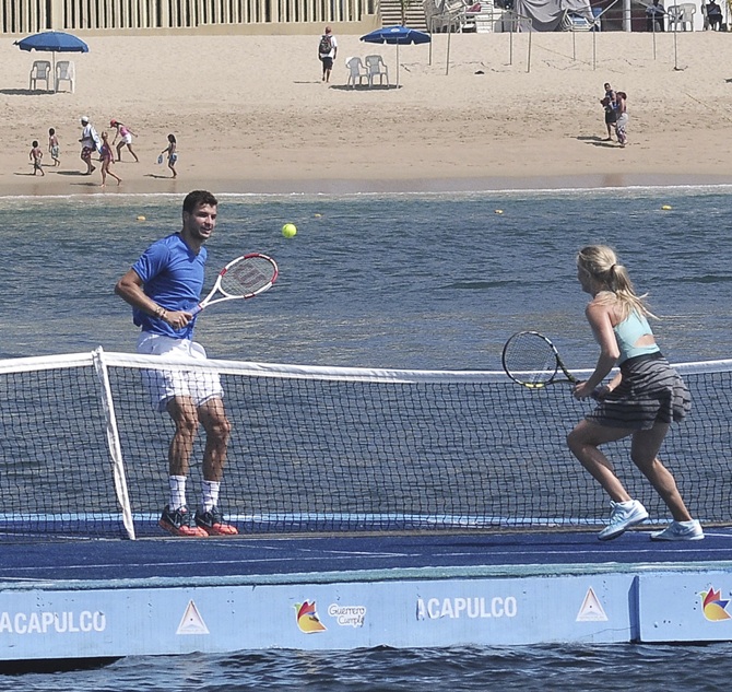 Grigor Dimitrov of Bulgaria returns the ball to Eugenie Bouchard of Canada in a friendly match on a floating court.