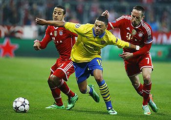 Bayern Munich's Thiago Alcantara and Franck Ribery (right) tackle Arsenal's Alex Oxlade-Chamberlain during their Champions League round of 16 second leg match in Munich, on Tuesday