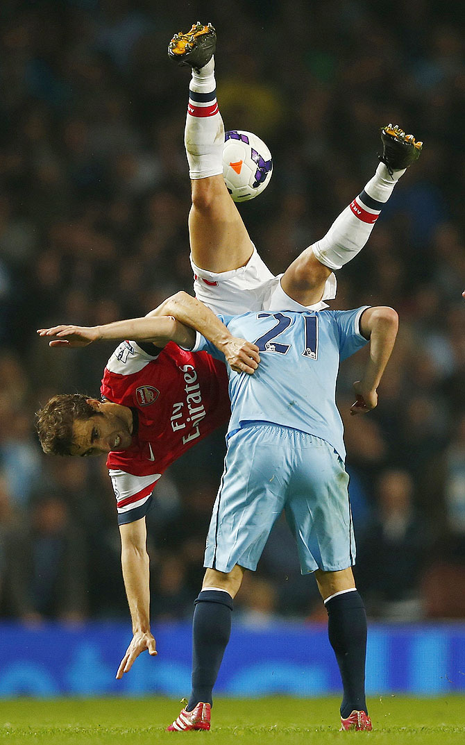 Arsenal's Mathieu Flamini (left) challenges Manchester City's David Silva during their English Premier League match at The Emirates Stadium in London on Saturday