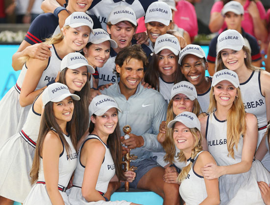 Rafael Nadal of Spain poses for a photograph with his winners trophy and model ball girls after victory in Madrid