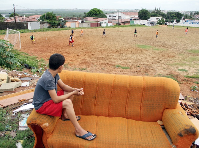 A boy sits on a discarded couch as he watches a Sunday 'pelada' soccer match in the Bom Pastor neighborhood of Natal, a World Cup host city