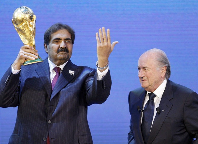 Qatar's Emir Sheikh Hamad bin Khalifa al Thani,left, holds up a copy of the World Cup he received from FIFA President Sepp Blatter