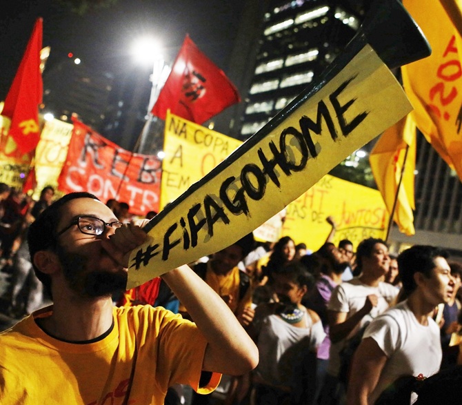 A demonstrator blows a horn during a protest against the 2014 World Cup, in Sao Paulo