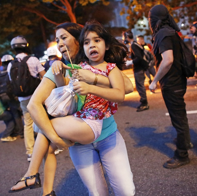 A woman carries her daughter away from their car, after it caught fire   driving through a flaming barrier during a protest against the 2014 World Cup in Sao Paulo