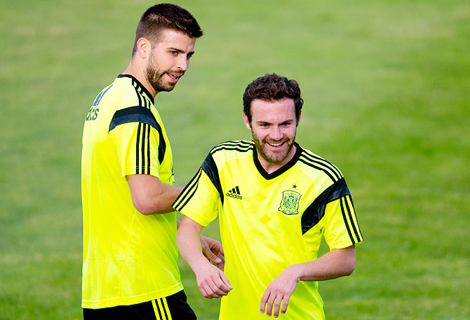 Gerard Pique (left) and Juan Mata of Spain joke during a training sesion.