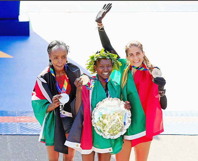 Mary Keitany (centre) of Kenya celebrates with the first place trophy alongside second place Jemima Sumgong (left) of Kenya and third place Sara Moreira (right) of Portugal during the trophy presentation after the New York City Marathon on Sunday