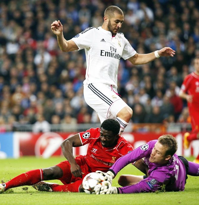 Liverpool's goalkeeper Simon Mignolet and teammate Kolo Toure clash as they stop a ball   past Real Madrid's Karim Benzema