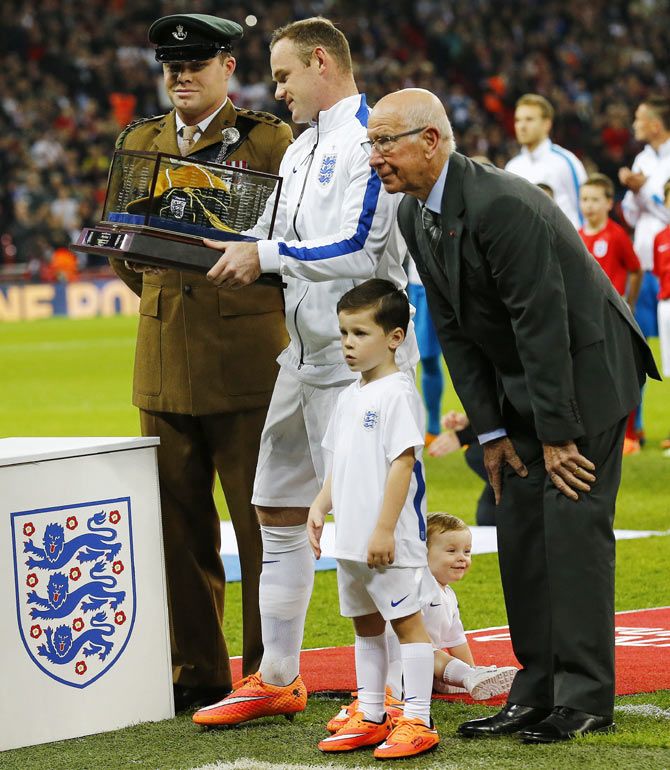 England captain Wayne Rooney stands with his sons Klay (on ground) and Kai after receiving a golden cap from Bobby Charlton (R) to mark his 100th cap