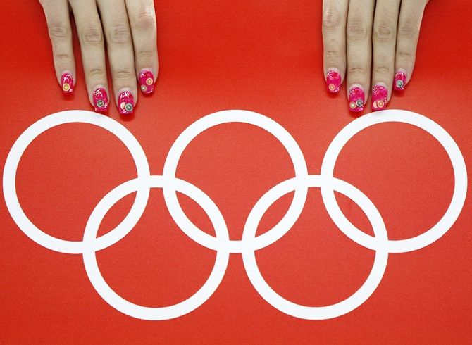 A volunteer's nails are seen beside the Olympic rings
