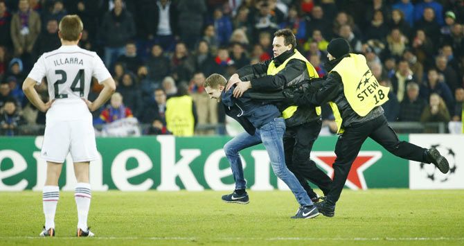 A fan is chased by stewards as he runs on the field during the Champions League Group B soccer match between FC Basel and Real Madrid on Wednesday