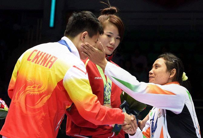 India's Sarita Devi (right) at the podium after refusing to accept the bronze medal