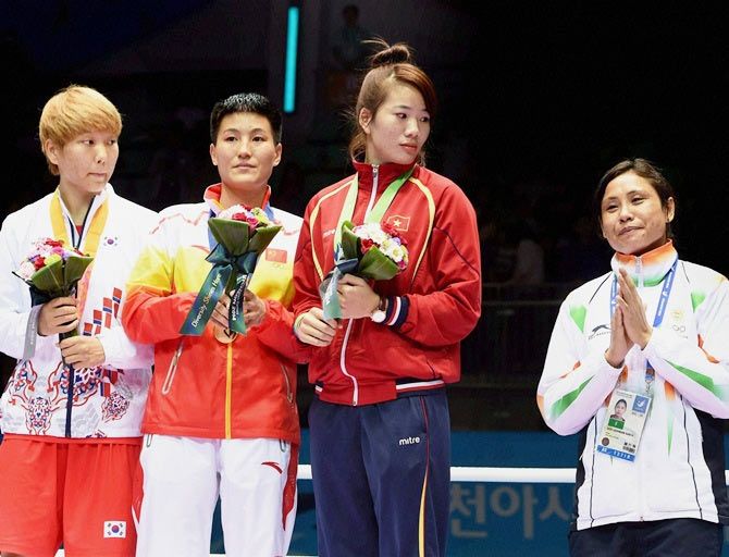 India's Sarita Devi gestures on the podium after refusing to accept the bronze medal.