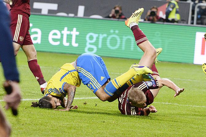 Sweden's Jimmy Durmaz falls over Russia's Igor Smolnikov during their Euro 2016 qualifying soccer match at Friends Arena