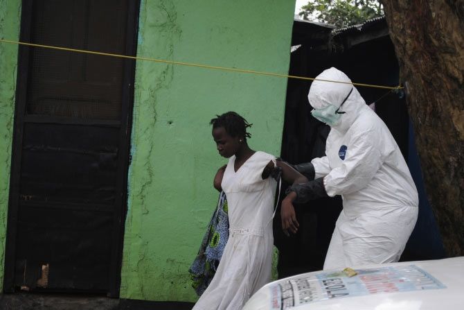 A health worker brings a woman suspected of having contracted the Ebola virus to an ambulance in Monrovia, Liberia